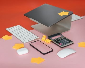 a cell phone, keyboard, mouse, and mouse pad on a pink surface